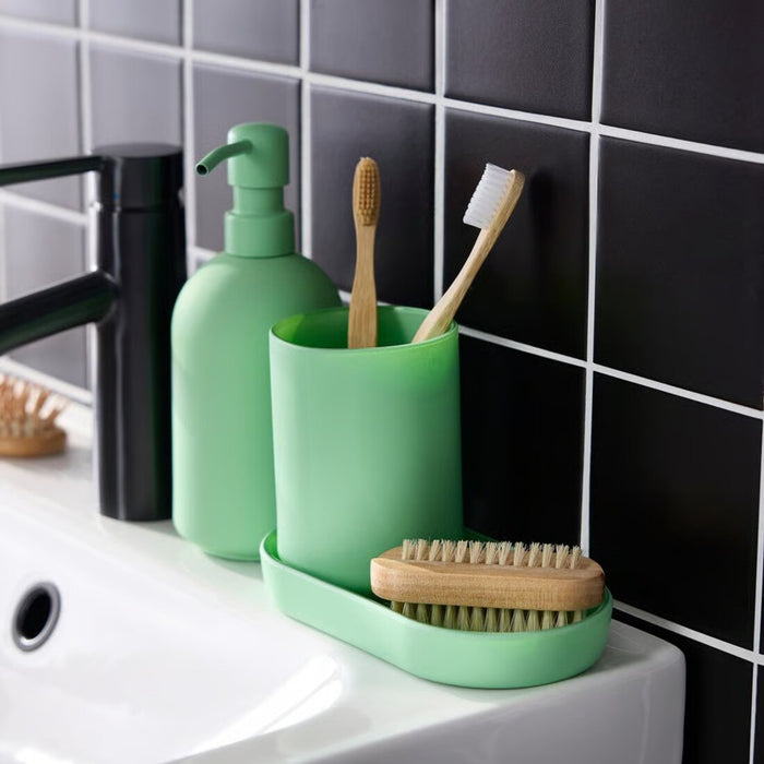 Green bathroom accessories including a soap dispenser, toothbrush holder, and scrub brush on a sink.