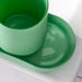 Green ceramic cup and saucer set on a white surface