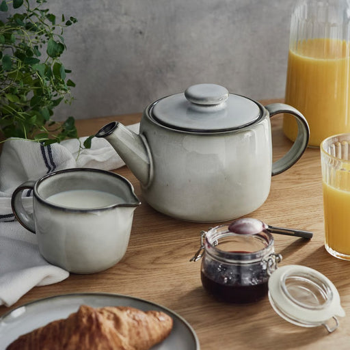 IKEA GLADELIG 1.2 l teapot placed on a wooden table, styled with matching dinnerware for a cohesive modern table setting.