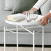 IKEA GLADOM white tray table placed beside a sofa with a cup and snack bowl on top