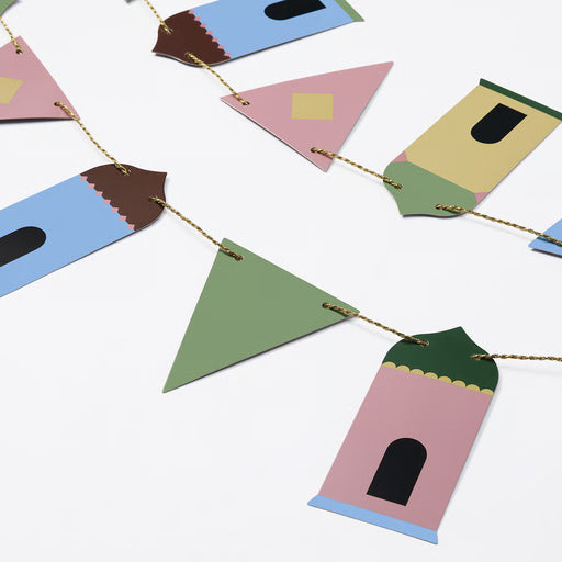 Close-up of IKEA GOKVÄLLÅ colourful paper houses and tassels on golden string pastel party decoration