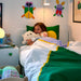 Child sleeping on IKEA GREJSIMOJS bedding with teddy bear and colourful pillows in bedroom