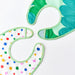 IKEA GRÖNFINK baby bibs 2-pack overhead flat lay showing green-trim and fruit-print designs