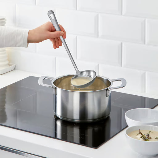 IKEA GRUNKA spatula being used to cook fish and tomatoes in a white frying pan on a stovetop