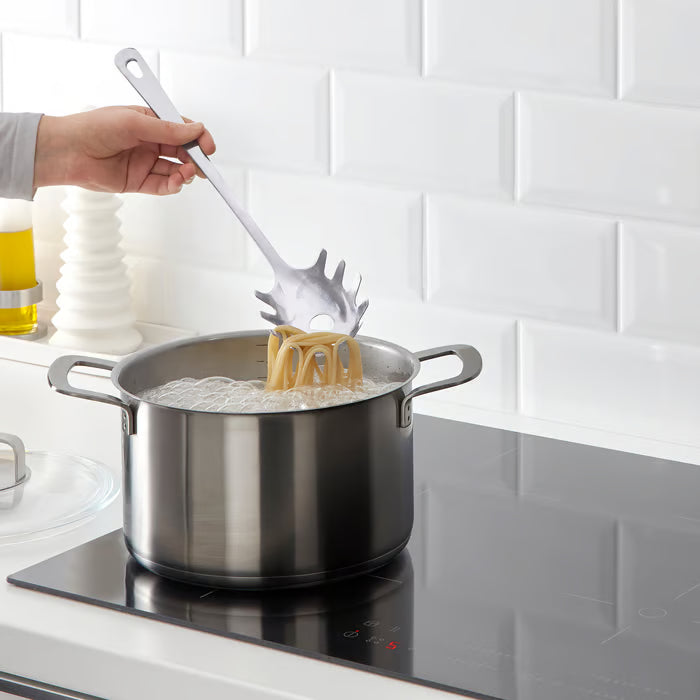 IKEA GRUNKA spaghetti server being used to plate pasta on a stovetop
