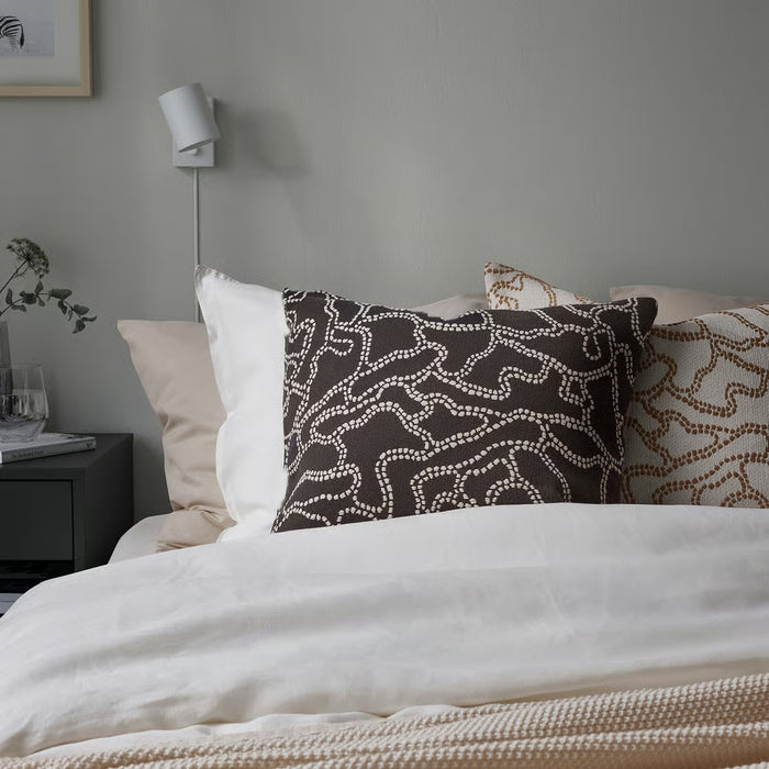 Bed with patterned pillows against a gray wall
