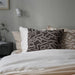 Bed with patterned pillows against a gray wall