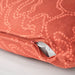 Close-up of a coral-colored pillow with zipper on a light gray background