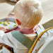 Minimalist Scandinavian-style baby bib from IKEA GULDVÄVARE collection in blush pink, with practical crumb catcher and soft fabric gentle on toddler's skin.

