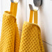 Two IKEA GULVIAL yellow cotton towels hanging neatly on hooks