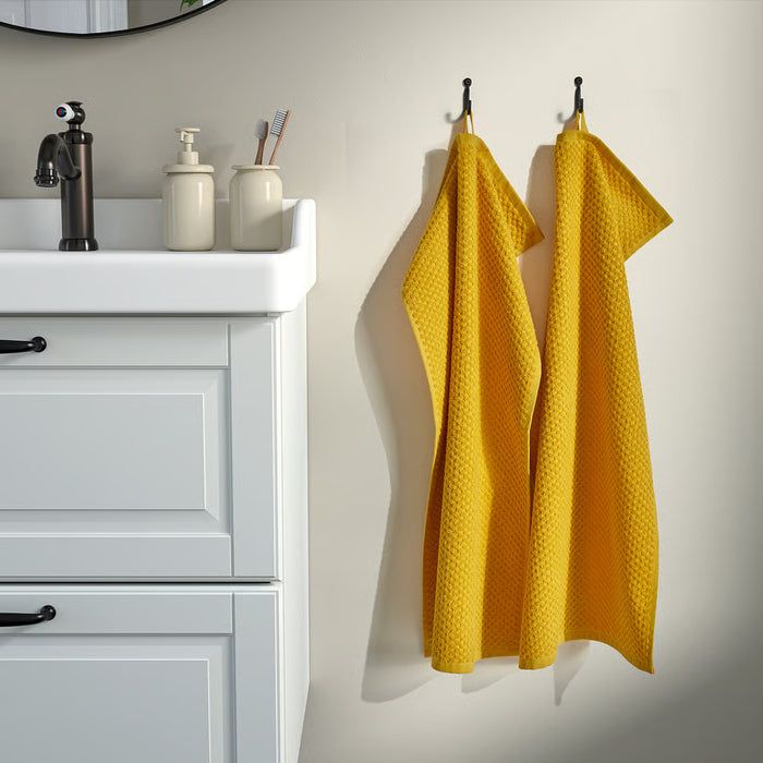 IKEA GULVIAL yellow hand towels hanging beside a white bathroom vanity with a black tap