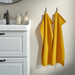 IKEA GULVIAL yellow hand towels hanging beside a white bathroom vanity with a black tap