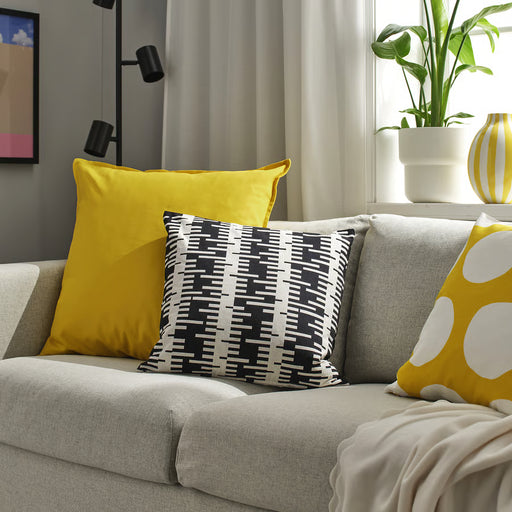 IKEA GURLI yellow cushion on a grey sofa beside a plant and vase by a window