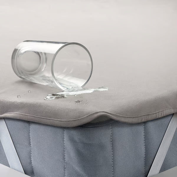 Water spilling on IKEA HAMPPALM waterproof mattress protector demonstrating liquid resistance