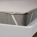 IKEA HAMPPALM grey waterproof mattress protector with elastic corner straps fitted on white bed