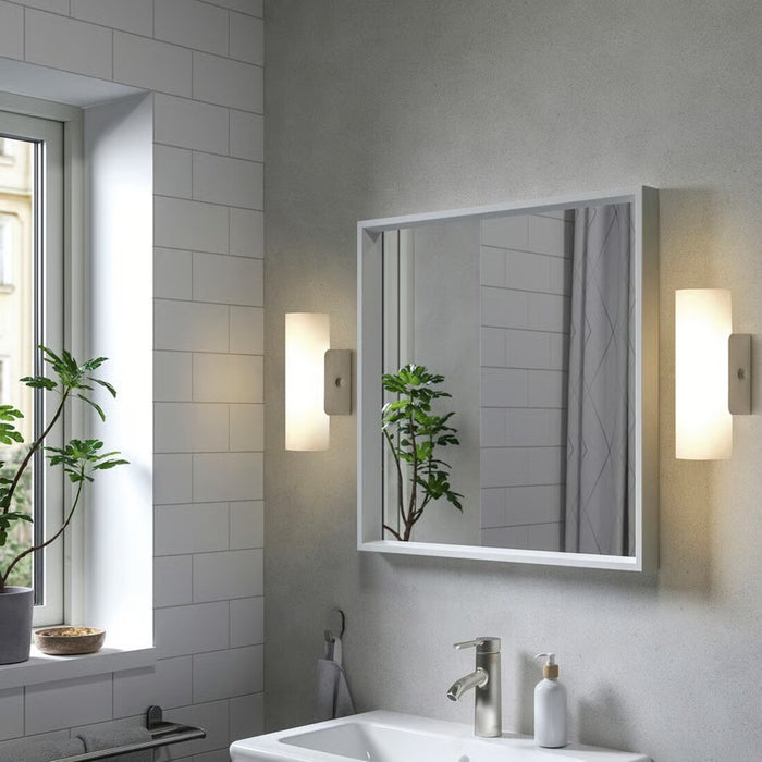 Modern bathroom with a mirror, sink, and decorative elements.