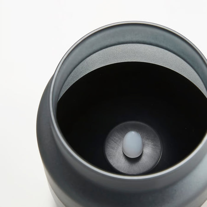 Close-up of IKEA HJULMÖJA LED candle with frosted glass and button in dark holder