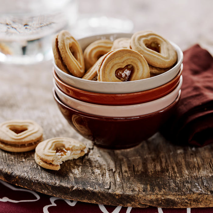 IKEA HÖSTAGILLE stacked red-brown bowls with heart-shaped cookies on a rustic wooden table