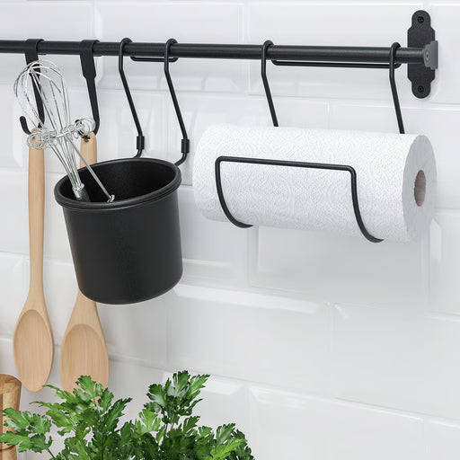 IKEA HULTARP black rail on kitchen wall with hanging utensils, hooks, and paper towel roll showing storage in use