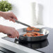 User flipping food with IKEA IDEALISK Cooking Tweezers in a kitchen.