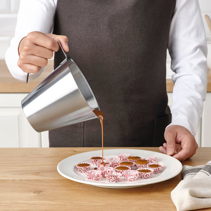 IKEA IDEALISK stainless steel jug being used to pour sauce over chocolate dessert on a plate