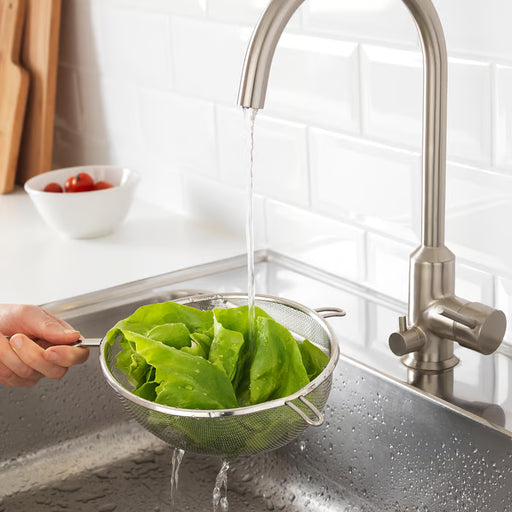 Hand rinsing lettuce under running tap using IKEA IDEALISK stainless steel strainer over kitchen sink