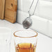 IKEA IDEALISK tea infuser hooked on rim of glass cup steeping loose-leaf tea on white countertop