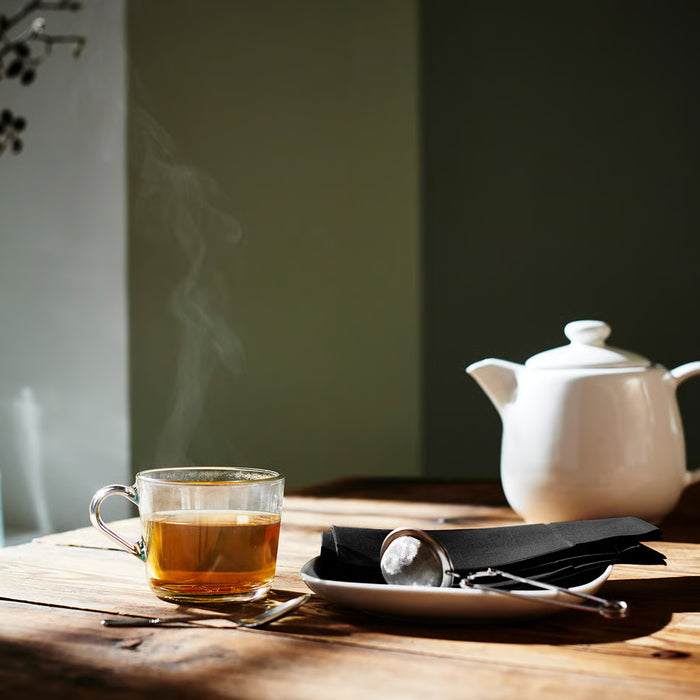 IKEA IDEALISK tea infuser placed on wooden table with loose-leaf tea and brewing accessories