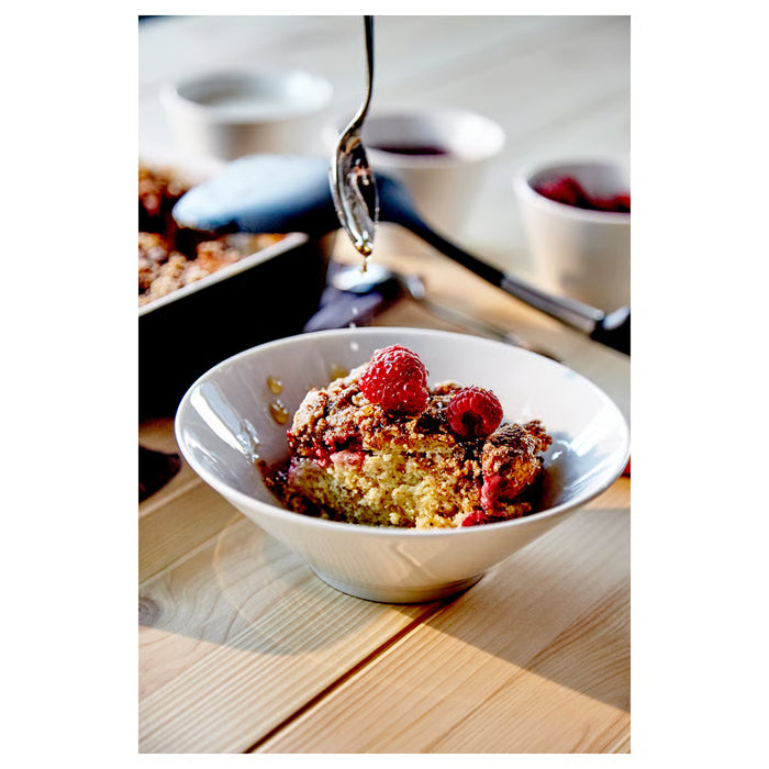 IKEA 365+ white bowl filled with raspberries and crumble on wooden dining table