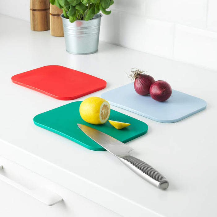 IKEA 365+ red blue and green chopping boards on white countertop with lemon knife and onions
