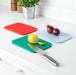 IKEA 365+ red blue and green chopping boards on white countertop with lemon knife and onions