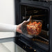  Person placing IKEA 365+ square glass container with pasta into oven demonstrating oven-safe use