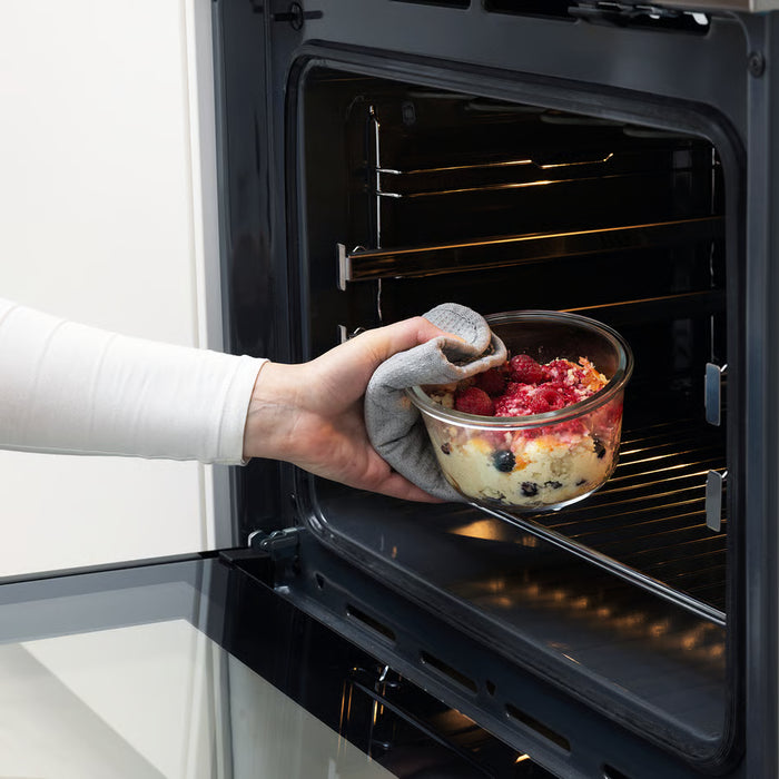 Person placing IKEA 365+ oven-safe glass container with fruit into oven