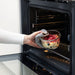 Person placing IKEA 365+ oven-safe glass container with fruit into oven