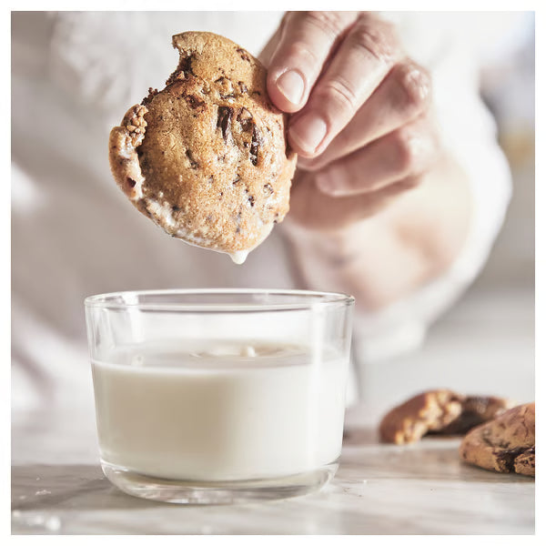 Hand dipping cookie into IKEA 365+ clear glass of milk everyday lifestyle use