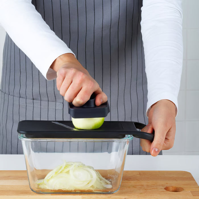  IKEA 365+ black mandoline slicer being used to slice onions directly into a container