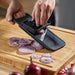 Person slicing onions on wooden board using IKEA 365+ black mandoline slicer
