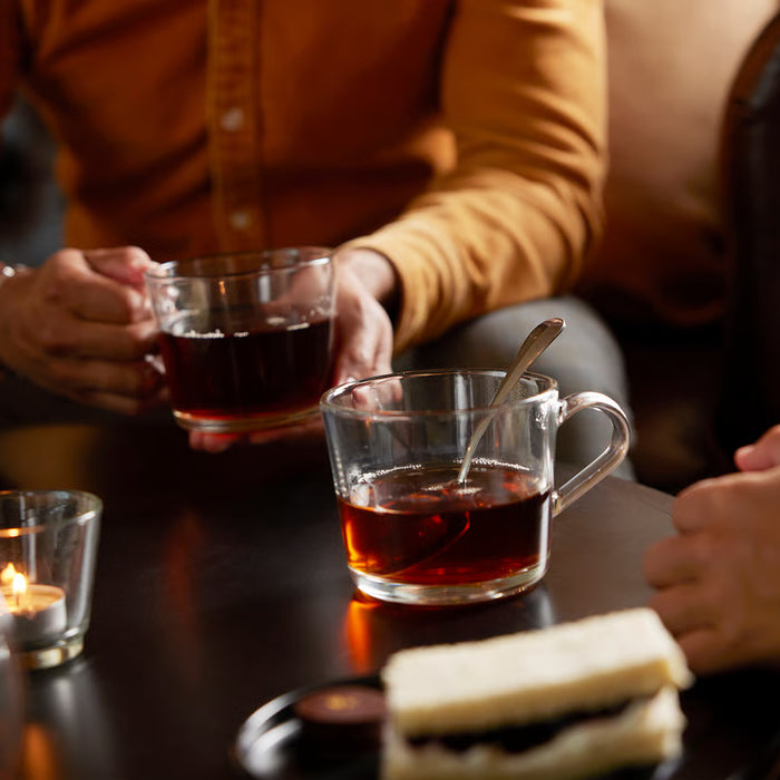 Two people holding IKEA 365+ clear glass mugs with tea showing sturdy handle and transparency