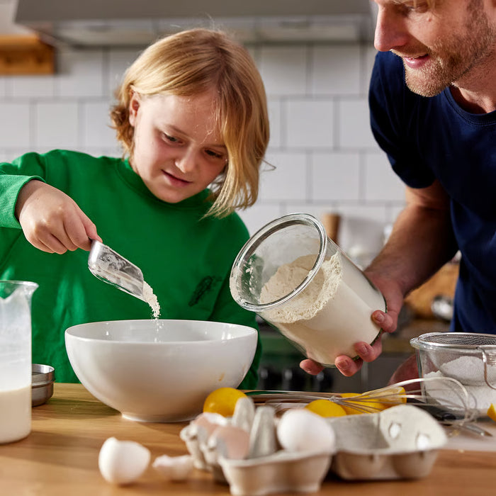  Parent and child baking together using IKEA 365+ metal scoops to measure ingredients in bowls