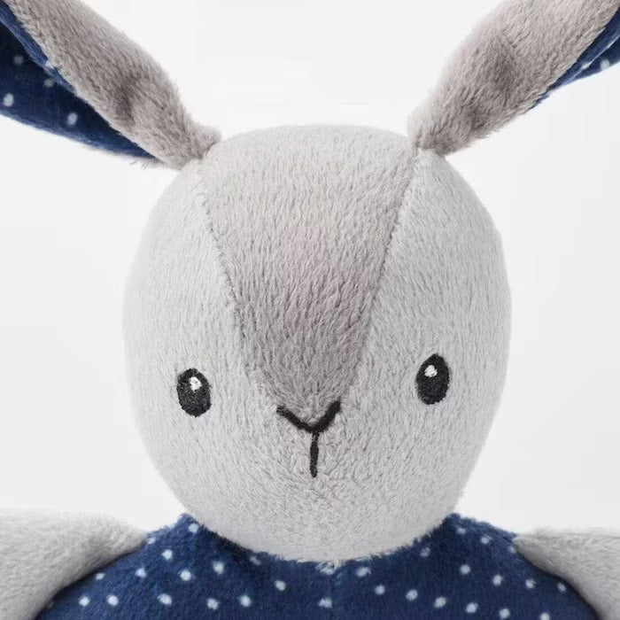  Hand holding IKEA GULLIGAST grey bunny rattle with blue polka-dot ring close-up view
