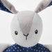  Hand holding IKEA GULLIGAST grey bunny rattle with blue polka-dot ring close-up view