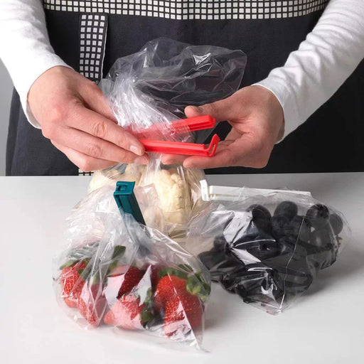 IKEA BEVARA sealing clip in use on a rolled‑up bag of potato chips in a kitchen pantry