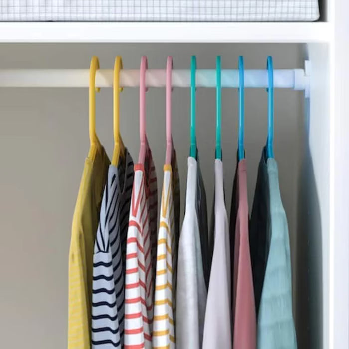 IKEA BAGIS children's coat hangers in blue, pink, and green hanging in a kid's wardrobe

