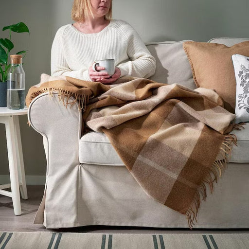 IKEA MYRULL light brown throw draped over armchair in living room warm cosy setting