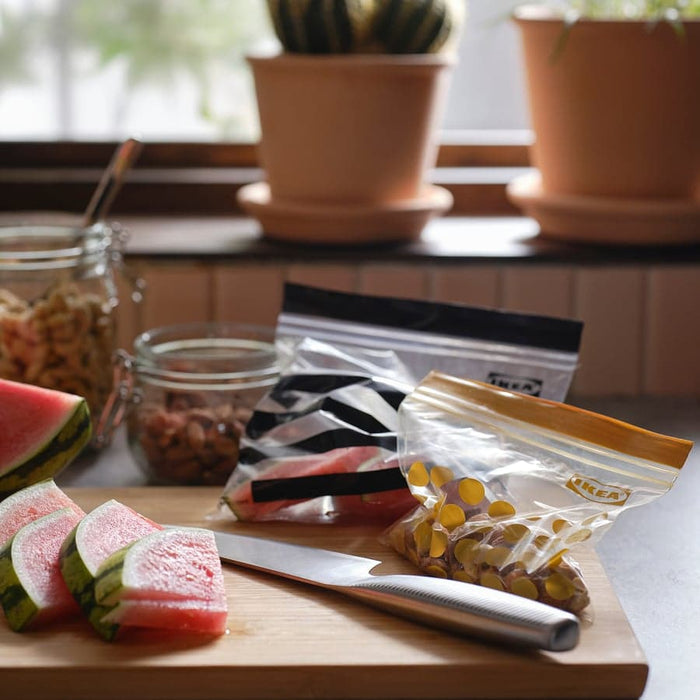 IKEA ISTAD sealed bags beside watermelon slices on wooden cutting board with jars and plants