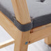 Underside of IKEA JUSTINA grey chair pad showing hook and loop fastener straps on wooden chair