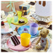 Colourful children's table setting with IKEA KALAS mugs plates bowls and toy food playful arrangement