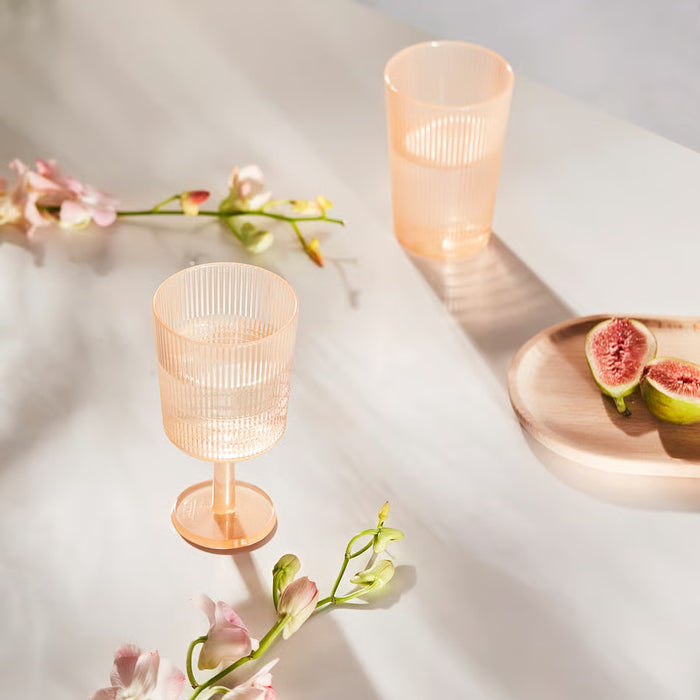  Two IKEA KALLSINNIG orange plastic wine glasses with vertical ribbed texture on white background