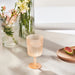 IKEA KALLSINNIG orange plastic wine glass styled outdoors near flower vases on a table