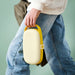 Person holding closed IKEA KAPTENSFISK yellow and white lunch box by its handle
